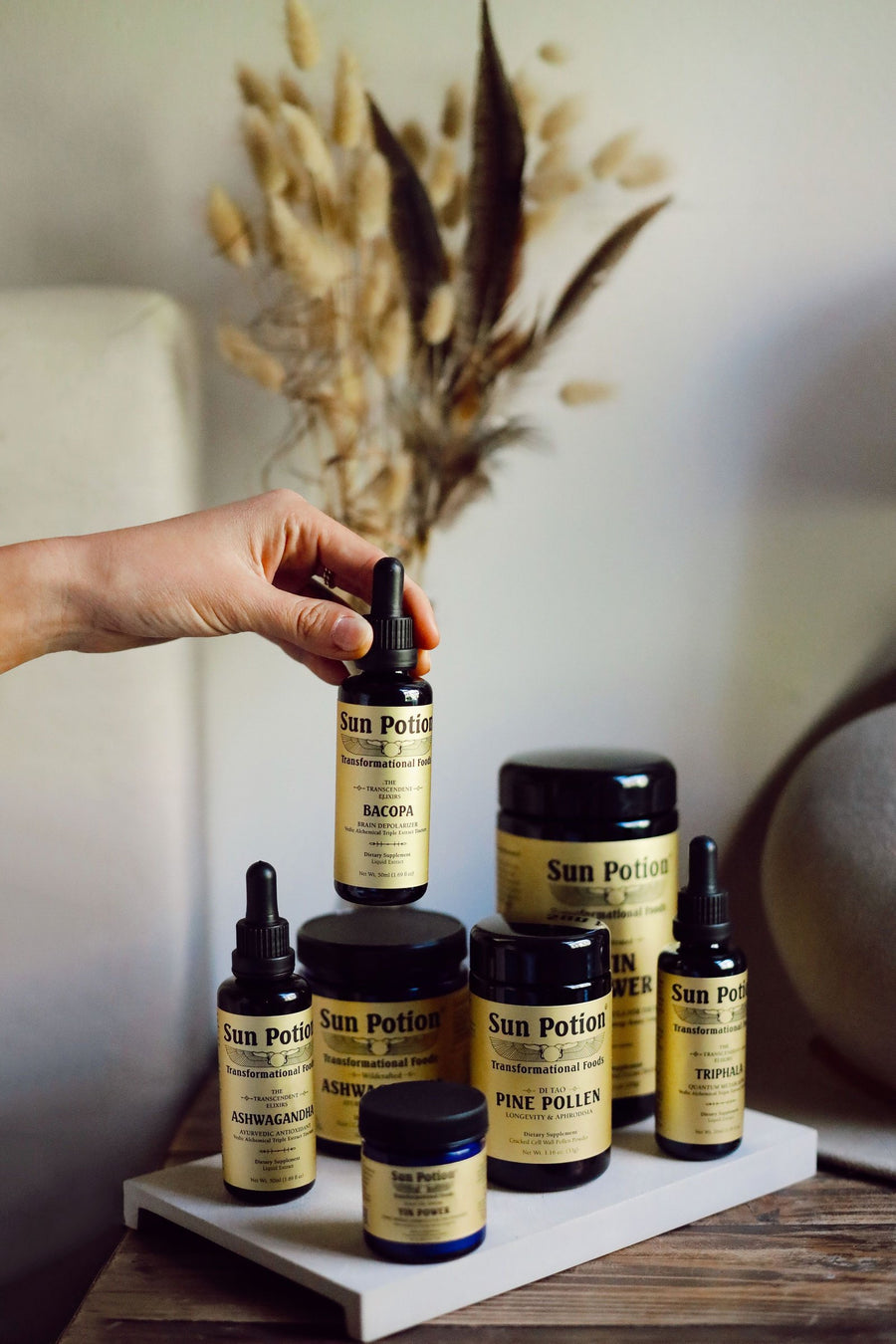 Hand taking a Sun Potion elixir from a shelf of jars and dropper bottles