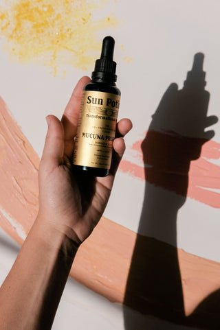 Hand holding a Sun Potion Mucuna elixir dropper bottle