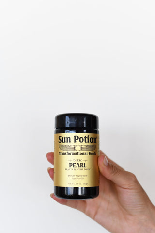 Hand holding a violet glass jar of Sun Potion Pearl