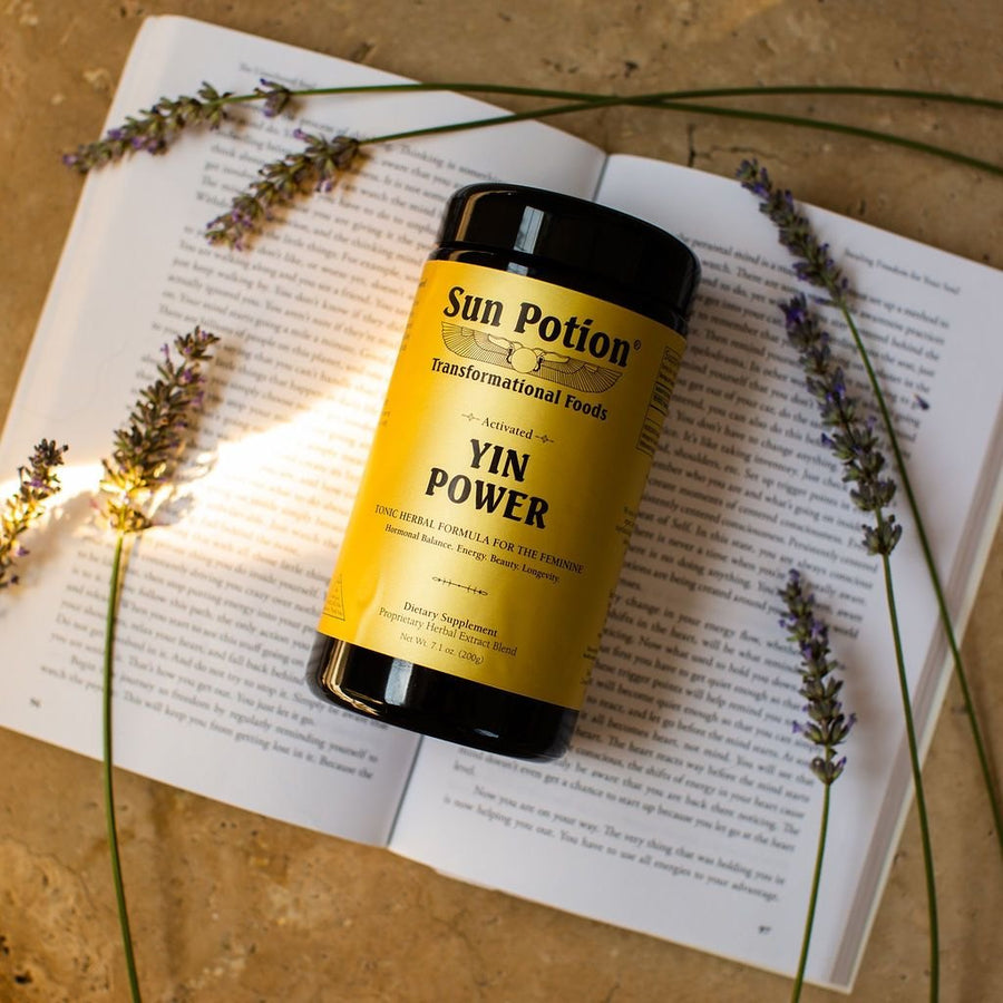 Jar of Sun Potion Yin Power on an open book with lavender