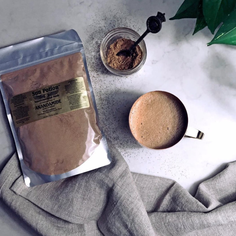 Pouch of Sun Potion Anandamide beside a cup of warm cacao