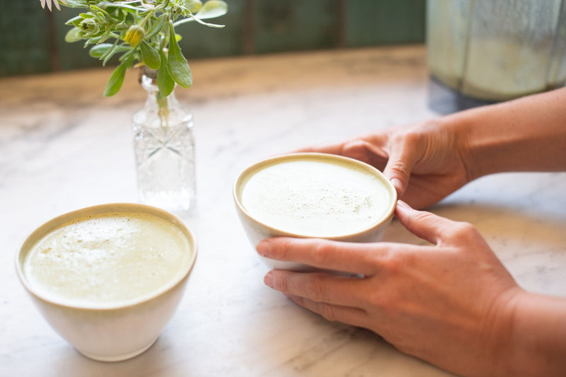 Hands around two lattes on a table